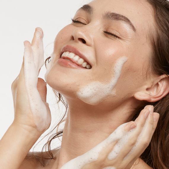 Young happy woman washing face with MooGoo Foaming Face Cleanser