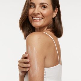 Smiling lady with moisturiser on her arm